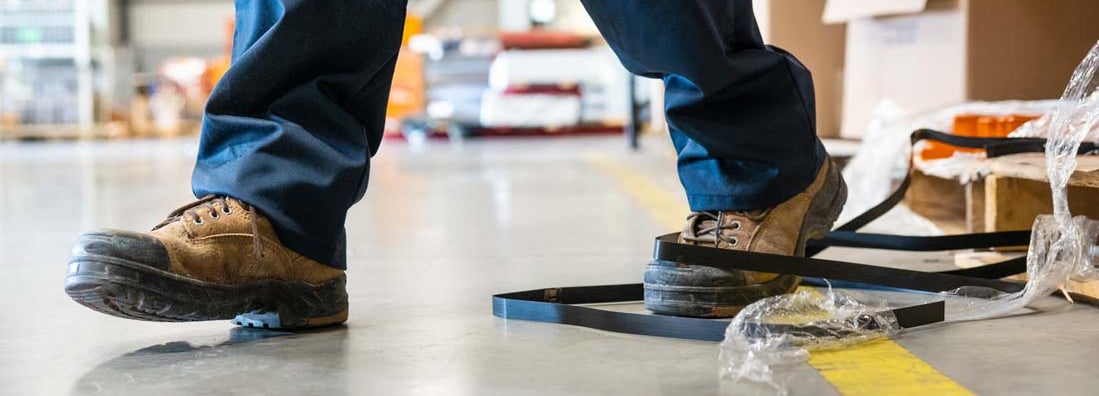 A worker in danger of tripping over a piece of metal strapping in a factory.